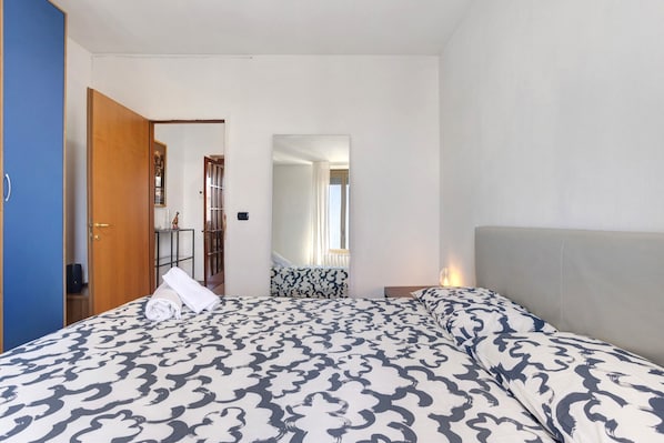 Une chambre d’hôtel avec un lit, une table de chevet, un miroir et une armoire.