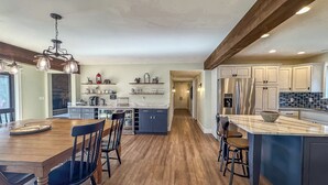 Une cuisine moderne dotée d’un îlot central, de planchers en bois et d’appareils électroménagers intégrés.