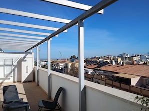 Un balcon offrant une vue sur le paysage urbain, avec notamment des bâtiments équipés de panneaux solaires.