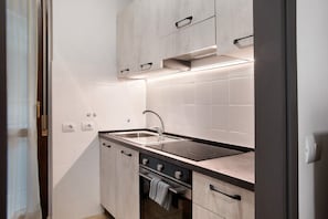 A modern kitchen with a sink, stove, and cabinets.