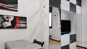 Ein modernes Zimmer mit Fernseher, einem Esstisch und Bildern an der Wand.