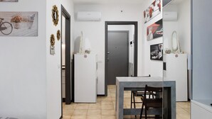Ein kleines Hotelzimmer mit Essbereich, Kleiderschrank und einer Tür zu einem weiteren Raum.