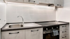 Eine Küche mit einem Edelstahl-Spülbecken, einer schwarzen Arbeitsplatte und einem eingebauten Backofen.