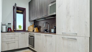 Une cuisine avec des meubles en bois, un four encastré, un four à micro-ondes et une fenêtre donnant sur un paysage verdoyant.