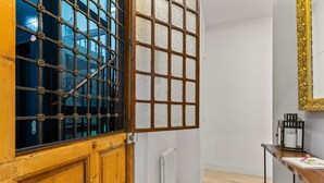 Una habitación con puerta de madera, un radiador, pared blanca y suelo de madera.