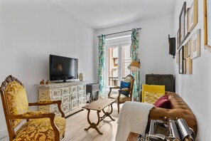 A living room with a television, a vintage typewriter, a sofa, a chair, a table, and a cabinet.