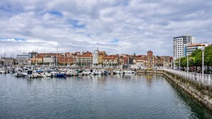 Un puerto deportivo con barcos amarrados, un muro de piedra y edificios con tejados rojos al fondo.