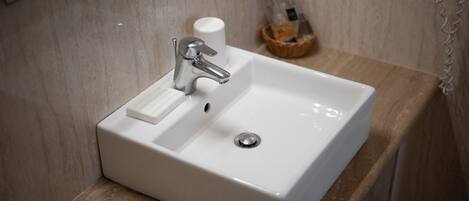A bathroom with a white sink, a mirror, and a soap dispenser on the countertop.