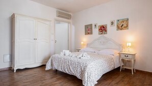 Ein Schlafzimmer mit Bett, Nachttischen, einem Kleiderschrank und Wandbildern.