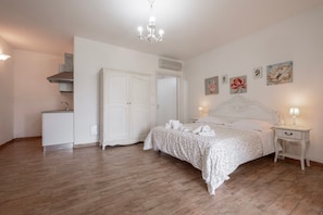 A bedroom with a bed, bedside tables, a wardrobe, and a kitchenette. - Apartment 'Salvia' with Shared Pool, Wi-Fi and Air Conditioning (Manciano)