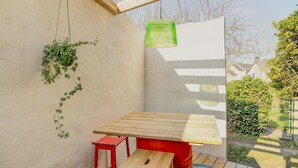 Una mesa de madera con un banco, una planta verde colgante y un barril rojo.