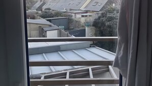 Vista desde un balcón con techo de metal, piso de madera y una puerta con cerradura.