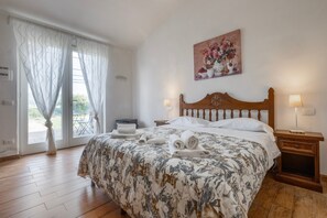 Una camera da letto con un letto, due comodini, un tavolino e un quadro, oltre a una finestra con tende.
