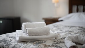 A neatly made bed with folded white towels and a lamp in the background. - Room 'Timo' with Shared Pool, Wi-Fi and Air Conditioning (Manciano)