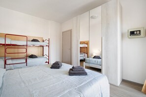A dorm-style room with bunk beds, a mirror, a wardrobe, and a bedside table.