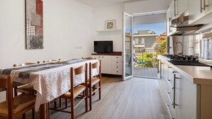 A compact kitchen with a dining area, a TV, and a balcony with a view. - Apartment '1 Piano' with Shared Terrace, Wi-Fi and Air Conditioning (Jesolo)