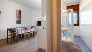 A modern kitchen with a dining area, a white sink, and a wooden floor. - Apartment '1 Piano' with Shared Terrace, Wi-Fi and Air Conditioning (Jesolo)