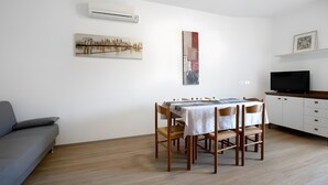 A modern living room with a dining table, sofa, TV, and artwork on the walls. - Apartment '1 Piano' with Shared Terrace, Wi-Fi and Air Conditioning (Jesolo)