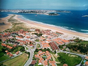Vue aérienne d’une ville côtière avec des immeubles résidentiels, une plage et un phare.
