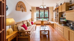 Ein gemütliches Wohnzimmer mit einer Couch, einem Tisch und einem Fernseher.