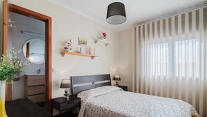 A bedroom with a bed, bedside tables, a mirror, a hanging lamp, and a window with curtains. - Room 'Duplo Com Wc Privada' with Shared Garden and Wi-Fi (Apúlia)