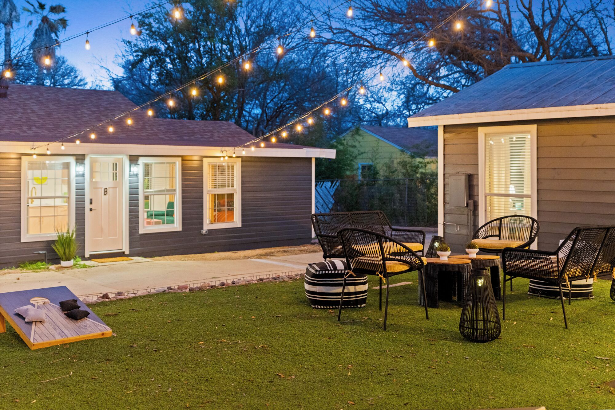 A two-story house with a patio area featuring outdoor furniture and string lights.