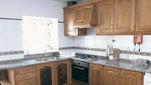 Une cuisine avec des meubles de rangement en bois, une cuisinière à gaz, un évier et un lave-vaisselle.