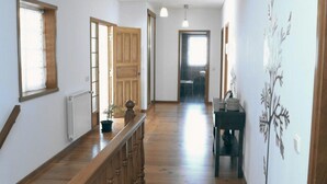 Un couloir doté d’un plancher en bois, d’une plante en pot, d’un radiateur et d’une porte donnant sur une autre pièce.