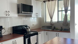 Eine moderne Küche mit weißen Schränken, einer Mikrowelle, einem Backofen und einer Holz Arbeitsplatte.