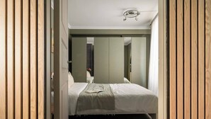 A bedroom with a bed, a mirror, and a wooden floor.