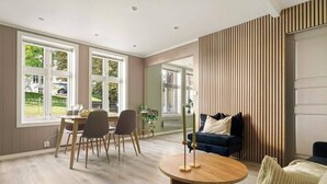 A modern living room with a dining area, large windows, and a view of the outdoors.