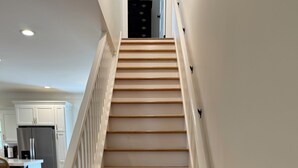 Eine Treppe mit weißen Geländern und Holzstufen, die zu einer Zwischenebene führen.