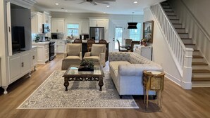 Ein geräumiges Wohnzimmer mit einer Couch, Sesseln, einem Couchtisch und einem Teppich.