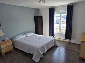 A bedroom with a bed, a nightstand, a wardrobe, and a window with curtains.