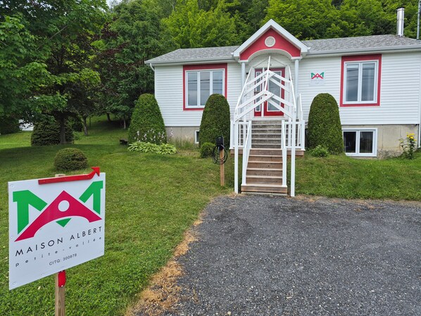 A house with a red and white exterior, a front porch, and a staircase leading to the entrance.