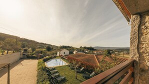 A residential area with a swimming pool, lounge chairs, and a stone building. - Casa da Pedra by ALPONTE (Venade)