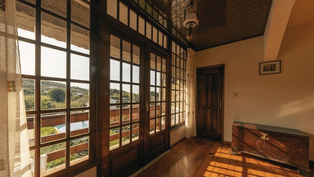 A room with large windows, a wooden floor, and a wooden chest. - Casa da Pedra by ALPONTE (Venade)