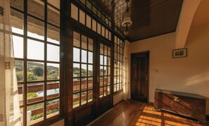 Una habitación con ventanas amplias, suelo de madera y un cofre de madera.