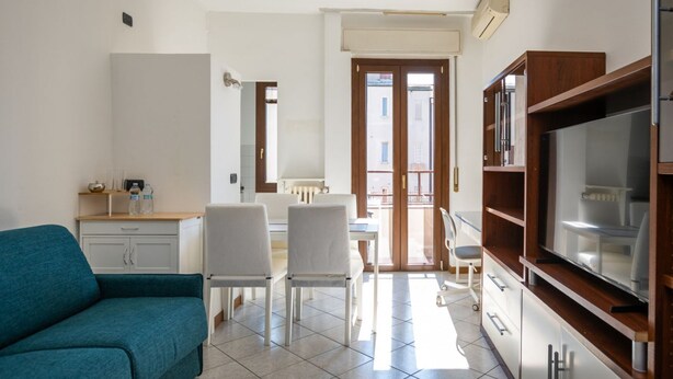 Un espacio habitable compacto con sofá, mesa de comedor, sillas y kitchenette.
