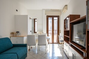 Een knus woongedeelte met een bank, eettafel, stoelen en een kitchenette.
