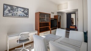 Una habitación de hotel con escritorio, sillas, televisor y estantería.