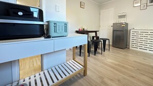 A compact kitchen with a toaster, a refrigerator, and a dining area with chairs. - Hot Spring Vacation House (Rotorua)