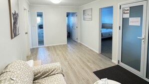 A hotel room with a sofa, a small table, a bed, and a door with a frosted glass panel. - Hot Spring Vacation House (Rotorua)