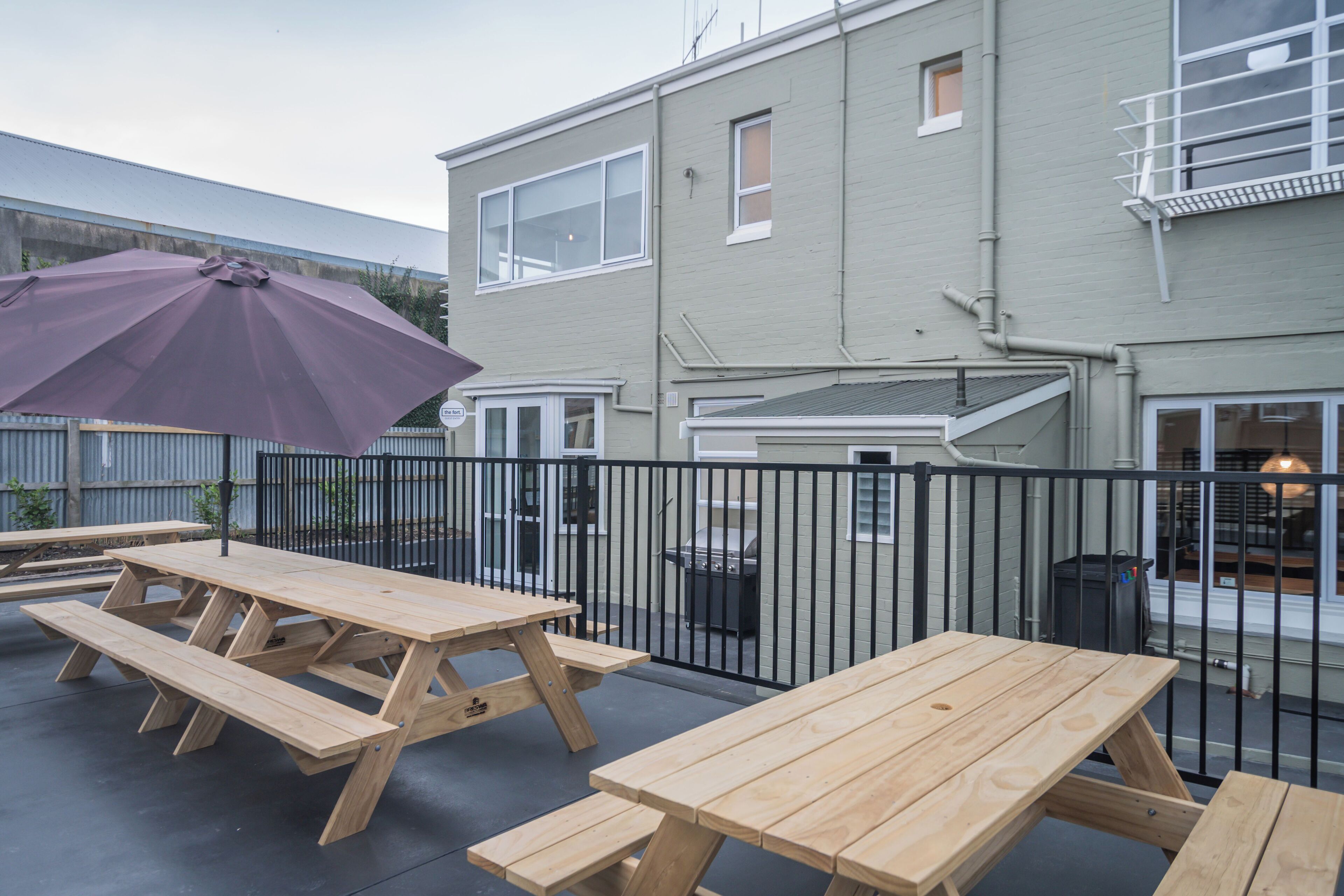 An outdoor patio area with picnic tables and a purple umbrella.