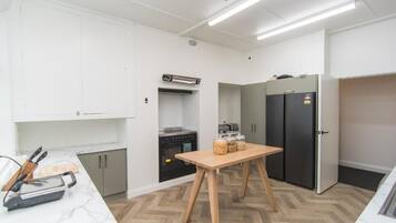 A modern kitchen with white cabinets, a wooden table, and a black refrigerator.