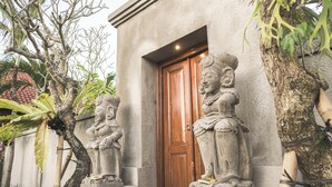 A building entrance with a wooden door, flanked by two stone statues. - Villa Puri Kembar – A Serene Escape with a Private Pool & Stunning Views (Bali)