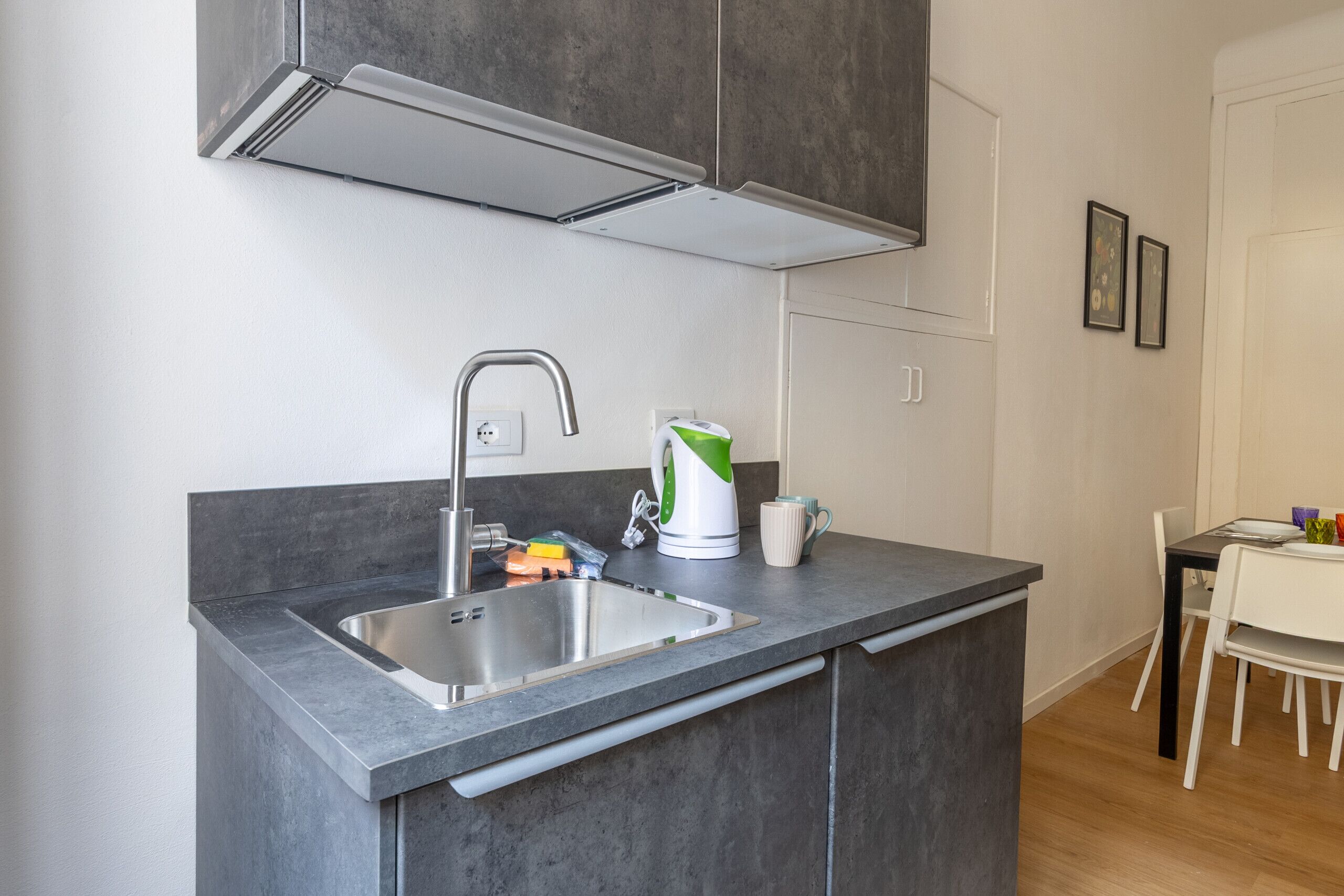 A modern kitchen with a built-in sink, stainless steel faucet, and a kettle on the countertop.