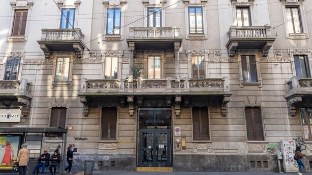 Un bâtiment historique doté d’une entrée centrale, de nombreuses fenêtres et de balcons.