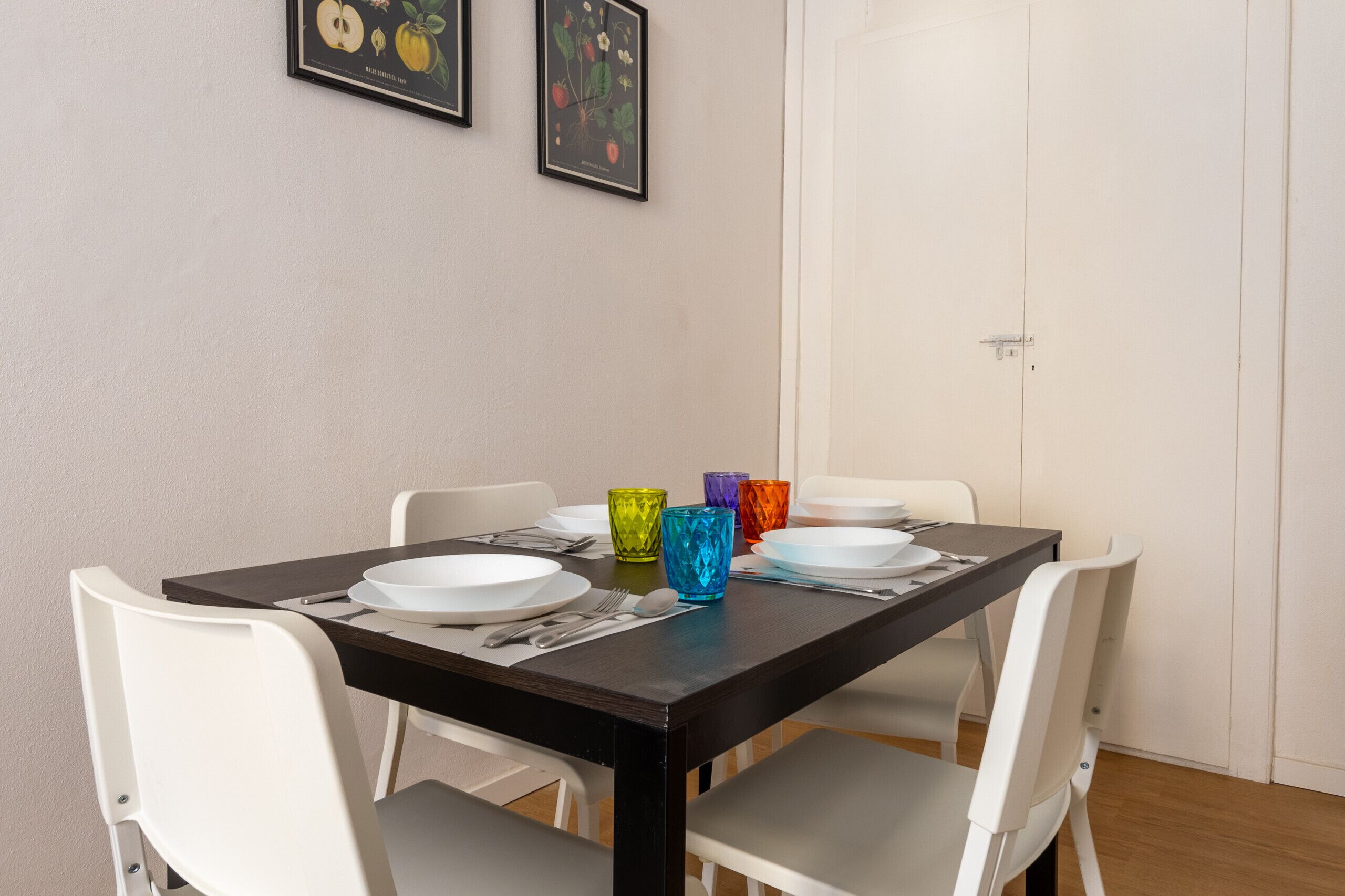 A dining table set with plates, cutlery, and colorful glassware.