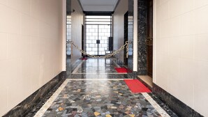 Un couloir doté d’un sol carrelé, d’une moquette rouge et d’une barrière à chaînes.